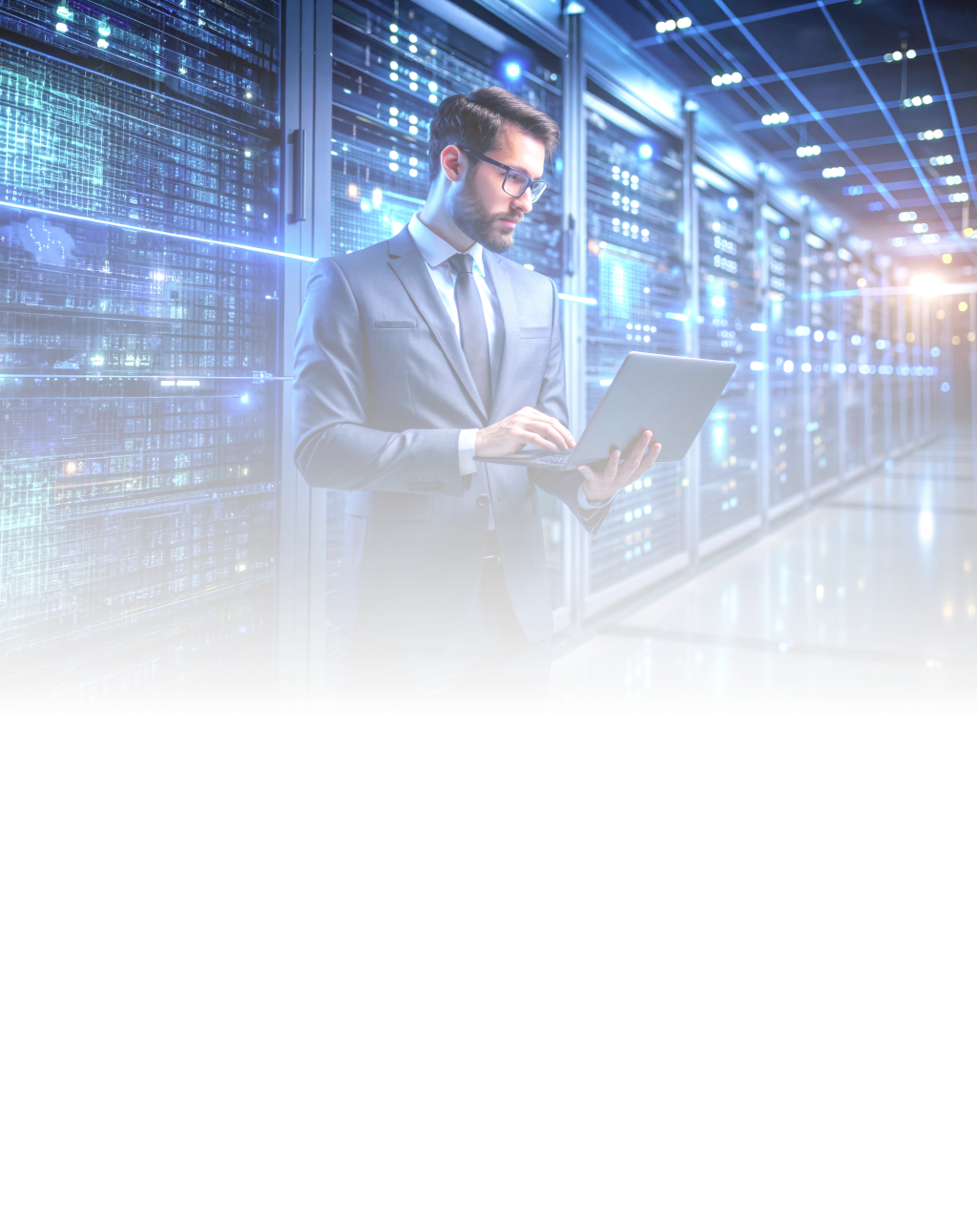 Man standing next to data servers holding a laptop in his hands