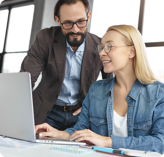Two professionals reviewing insurance software on a laptop