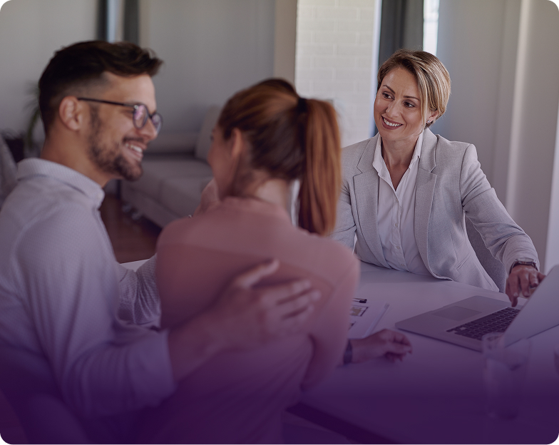 A female insurance agent and two clients reviewing documents at a desk