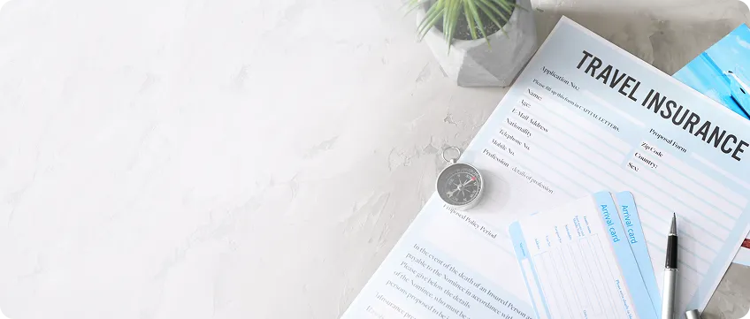 Travel insurance policy documents with a pen and compass on a desk
